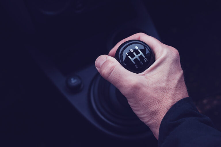 Male hand changing gear in the car while driving the motor vehicle, ultra violet toned shadows